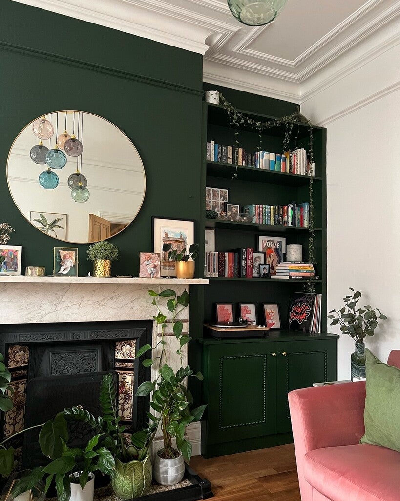 Living room with green walls, pink sofa, and bookshelf.