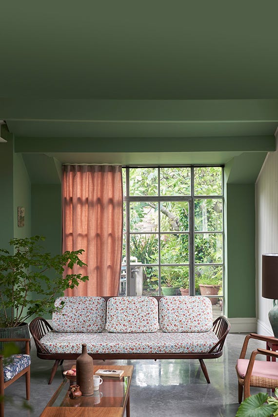 Living room with a floral-patterned sofa, large window, and green walls.