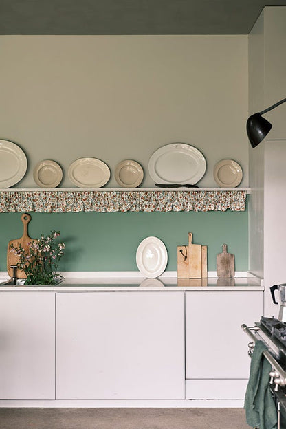 Kitchen with white cabinets, a green wall, and decorative plates on a shelf.