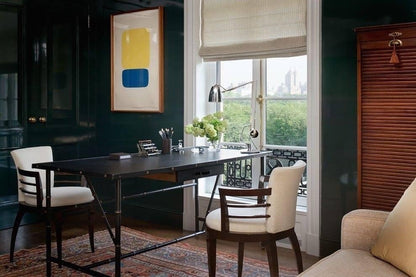 Dining room with a table, chairs, and a large window with a view of greenery.