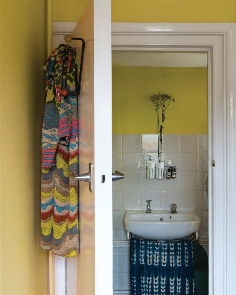Bathroom with yellow walls, sink, and colorful towels.