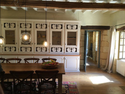 Dining room with wooden table, chairs, and white paneled walls.