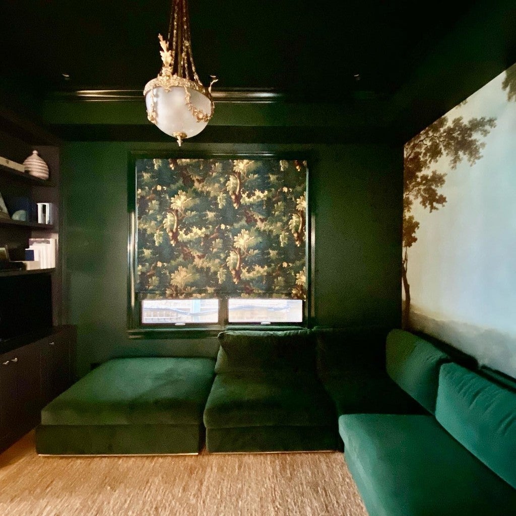 Green velvet sofa in a room with a decorative window and chandelier.