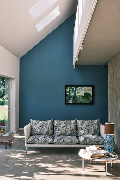 Modern living room with a blue wall, white sofa, and decorative items.