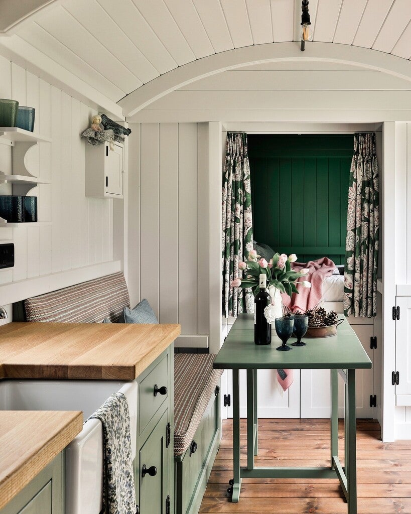 Small living space with wooden bench, green table, and decorative elements.