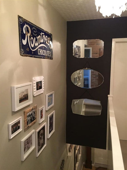 Wall with framed photos and a vintage-style 'Rountree Chocolates' sign, with a blackboard with mirrors attached.
