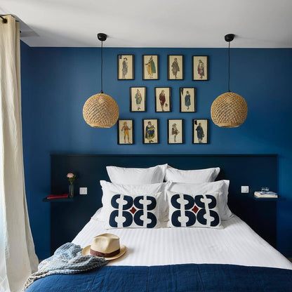 Bedroom with blue walls, white bedding, and framed pictures on the wall.