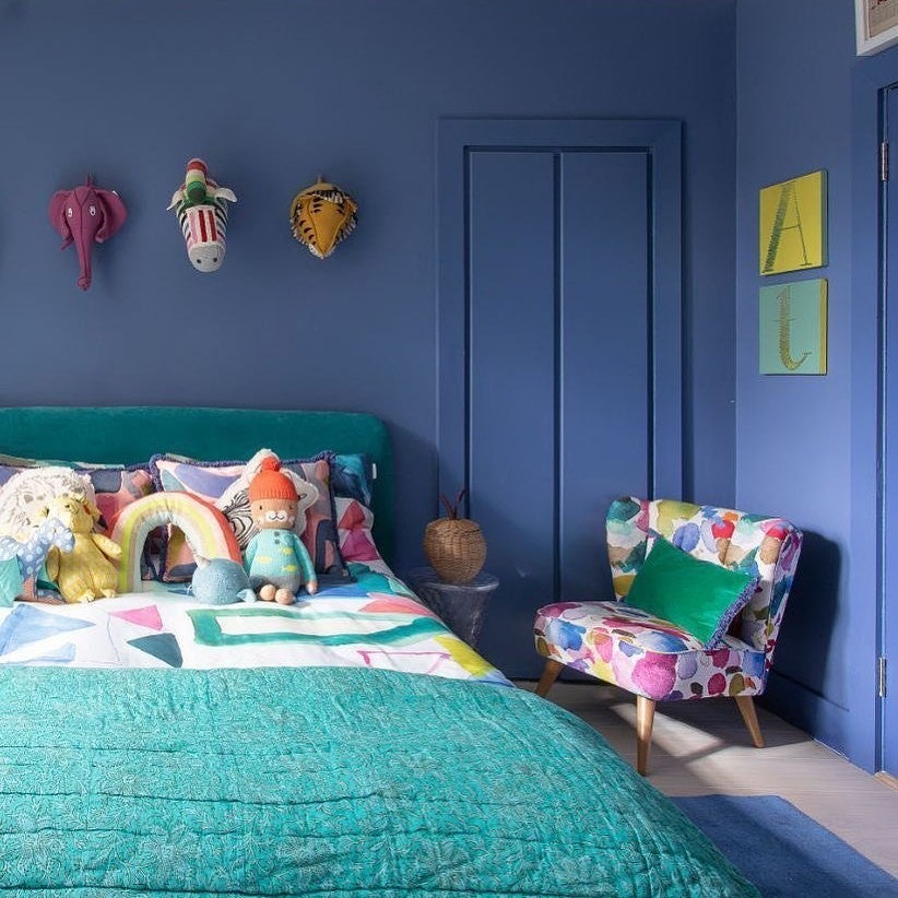 Children's bedroom with blue walls, colorful furniture, and decorative items.