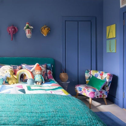 Children's bedroom with blue walls, colorful furniture, and decorative items.