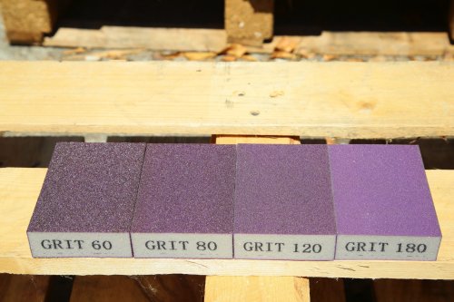 Four sandpaper sheets with different grits on a wooden surface