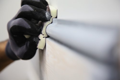 Person wearing gloves applying a white substance to a gray surface