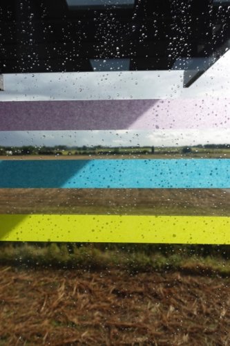 Raindrops on a window with a striped pattern of purple, blue, brown, and yellow.