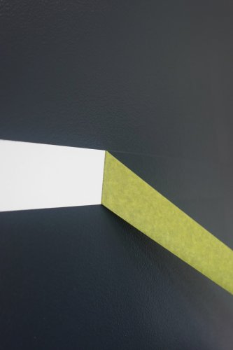 a dark wall with a green tape being peeled away to reveal white underneath leaving a perfect straight line.