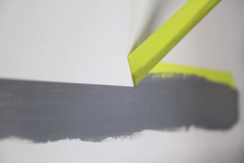 Close-up of gray paint swatch with a yellow tool on a white background