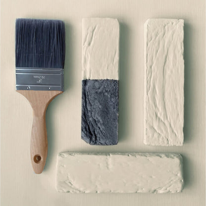Paint brush with gray paint on a textured white surface