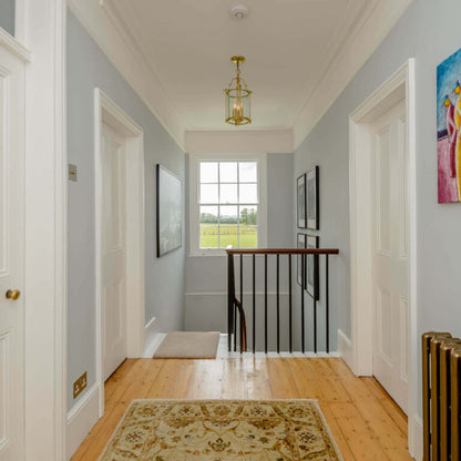 Hallway with wooden floor, rug, and staircase leading to a window.