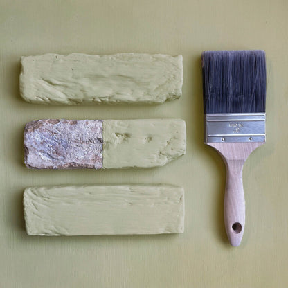 Three swatches of paint and a paintbrush on a beige background