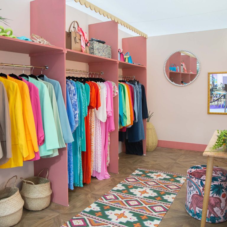 Colorful clothing arrangement in a room with pink shelves and a patterned rug.