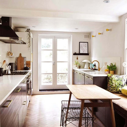Modern kitchen with white countertops, wooden floor, and a dining area.
