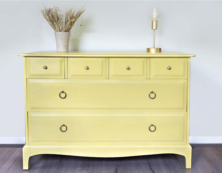 Yellow dresser with decorative items on a plain background