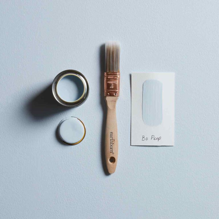 Paintbrush, paint can, and paper on a light blue background