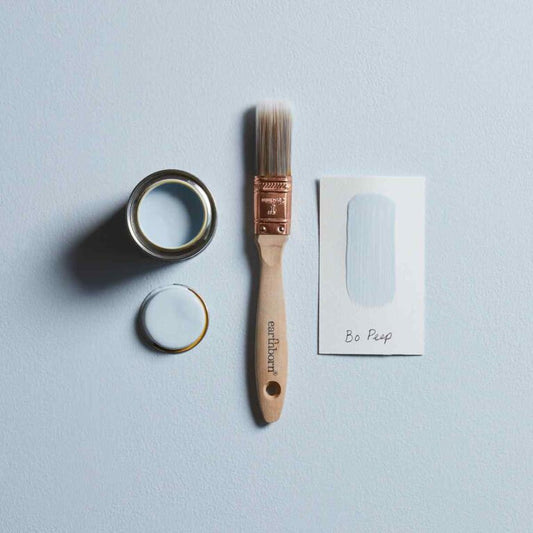 Paintbrush, paint can, and paper on a light blue background