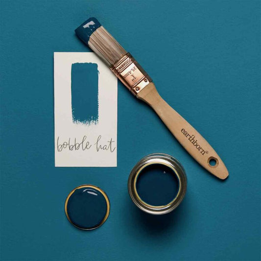 Paintbrush and paint container with 'bobble hat' color swatch on a teal background