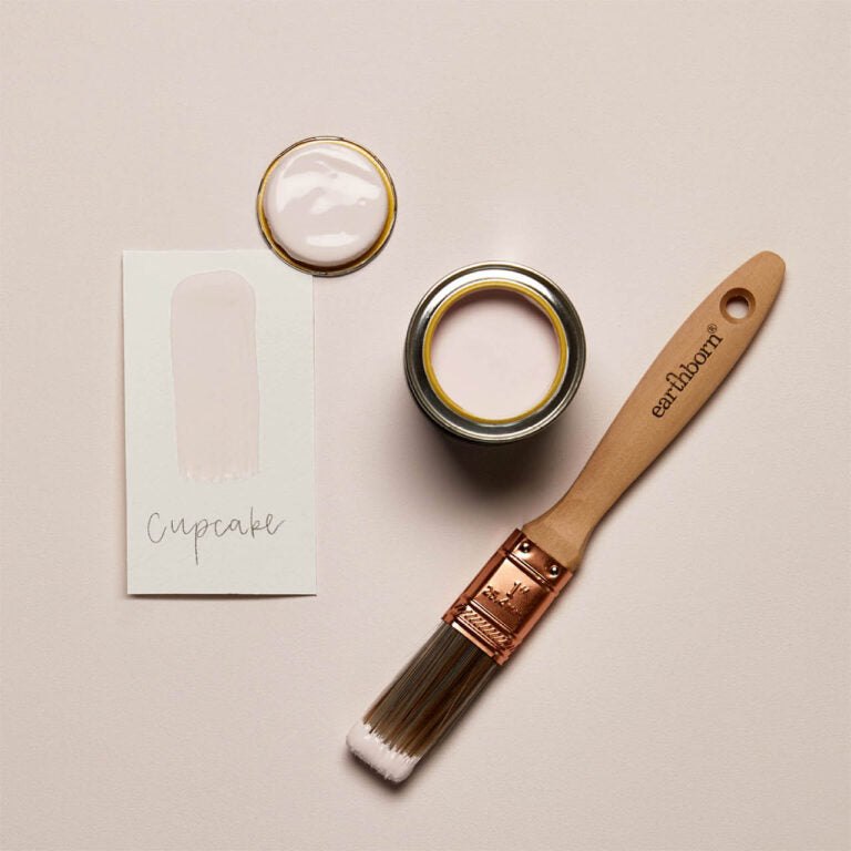 Paint can, brush, and swatch card on a beige background