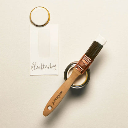 Paintbrush with wooden handle and metal ferrule on a light background