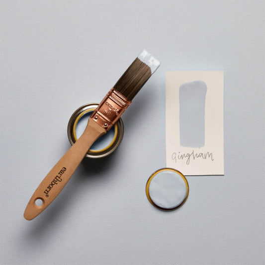 Paintbrush, paint can, and sample card on a gray background