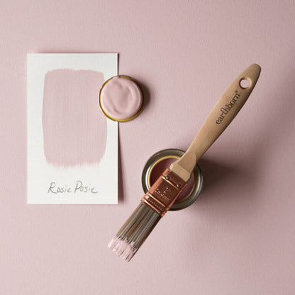 Paintbrush with 'earthborn' handle and container of pink paint on a pink background