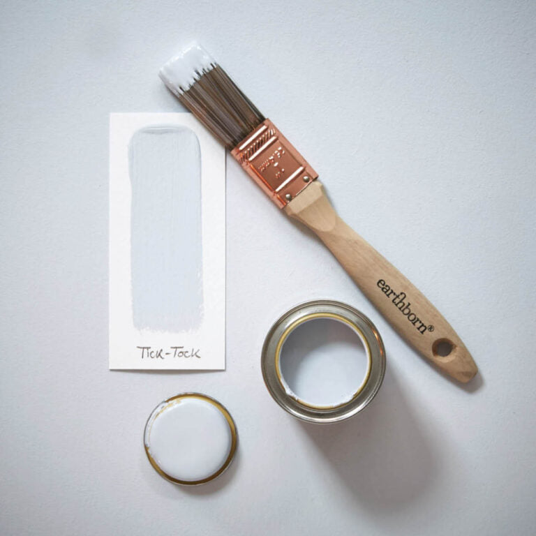 Paint brush and open paint can with 'earthenborn' branding on a light gray background