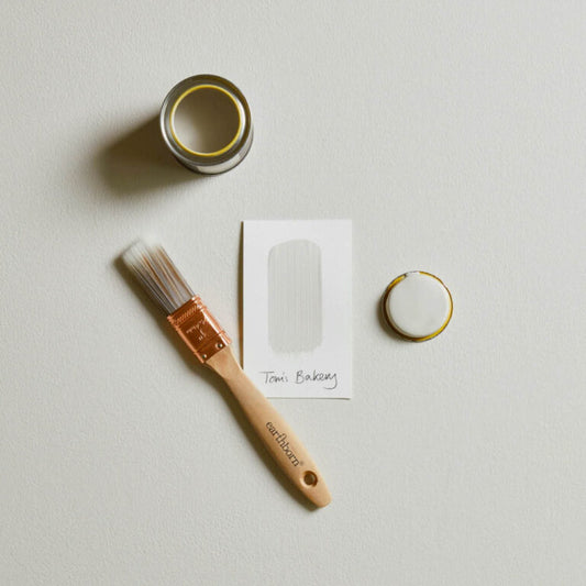 Paintbrush, small container, ring, and card on a light gray background