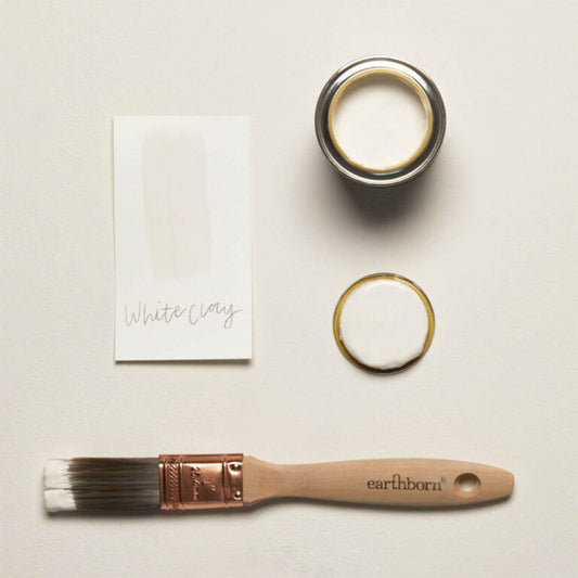 Paint can, brush, and card with 'White Clay' on a light background