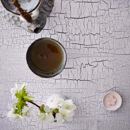 Tea cup with teapot and flowers on a textured white surface