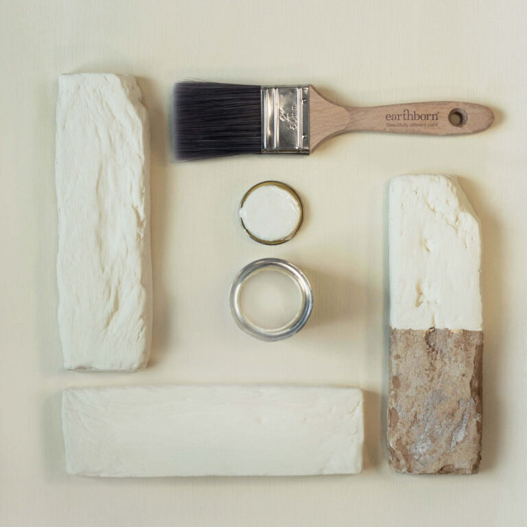 Paintbrush, paint containers, and textured stones on a light background