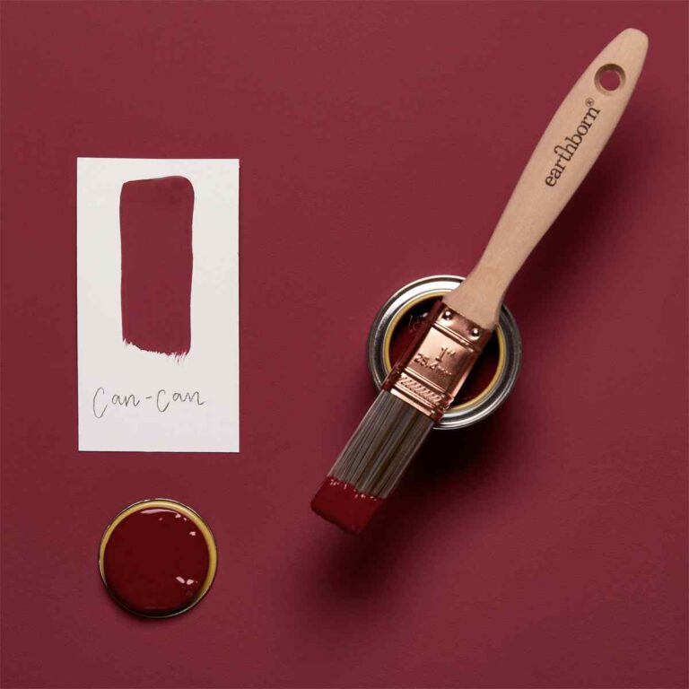 Paintbrush with red paint and color swatch on a red background