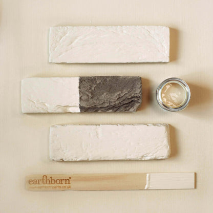 Set of natural skincare products including soap, cream, and wooden tool on a beige background with 'earlhamborn' branding.
