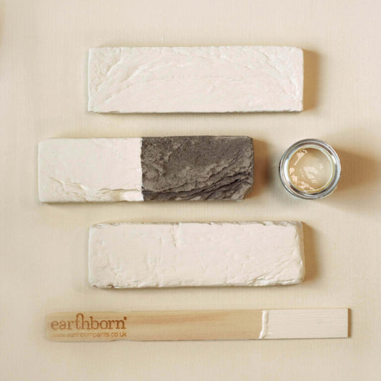 Set of natural skincare products including soap, cream, and wooden tool on a beige background with 'earlhamborn' branding.