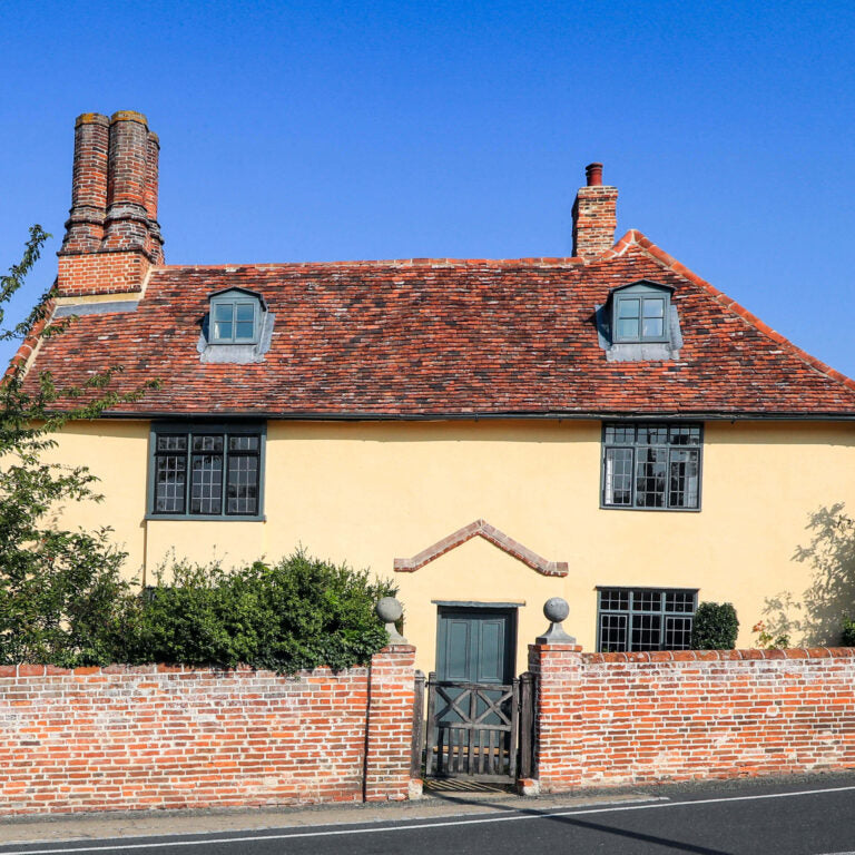 Traditional yellow house with red roof and brick walls on a clear day