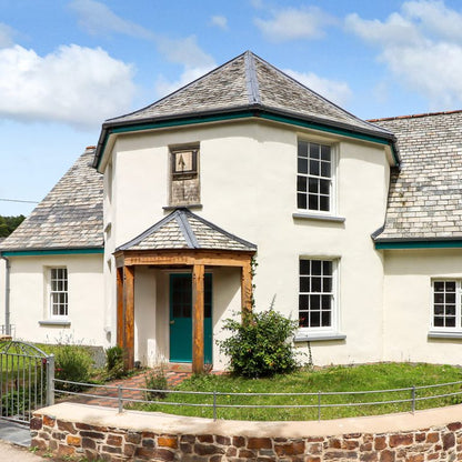White house with a green door and wooden porch under a blue sky.