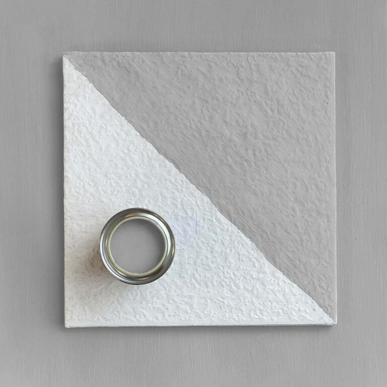 White textured square with a circular metallic object on a gray background