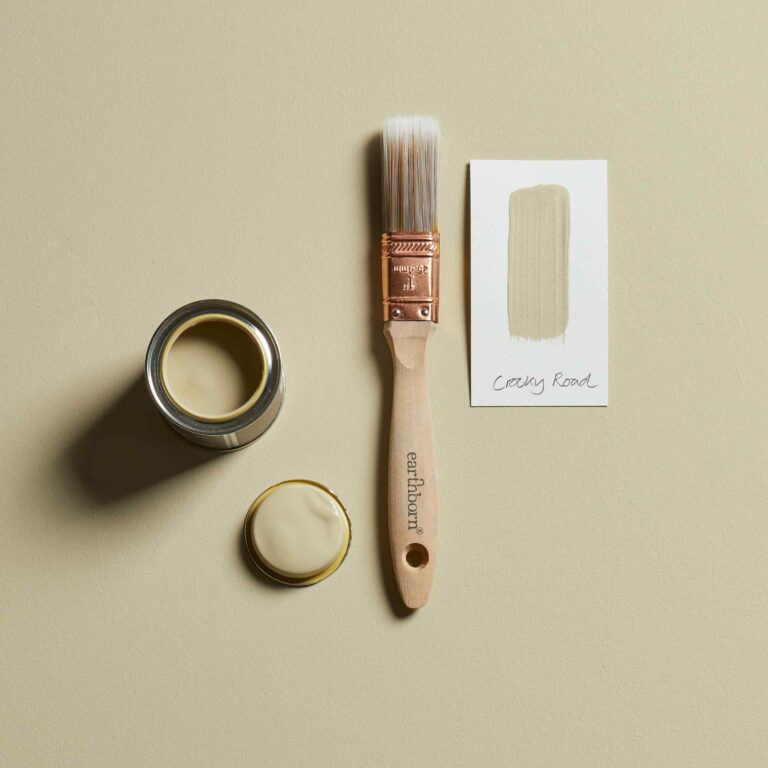Paint can, brush, and packaging on a beige background