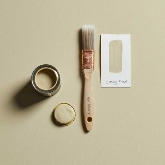 Paint can, brush, and packaging on a beige background