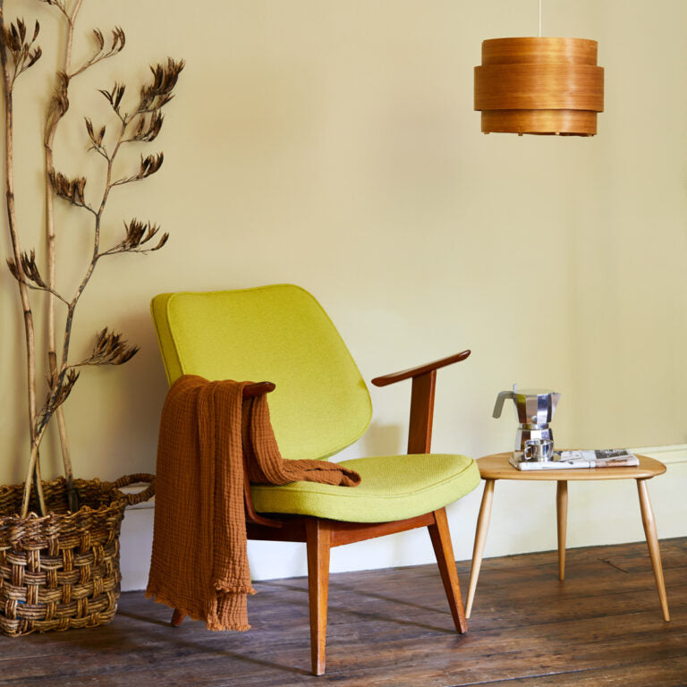 Green armchair with a wooden table and lamp in a room setting