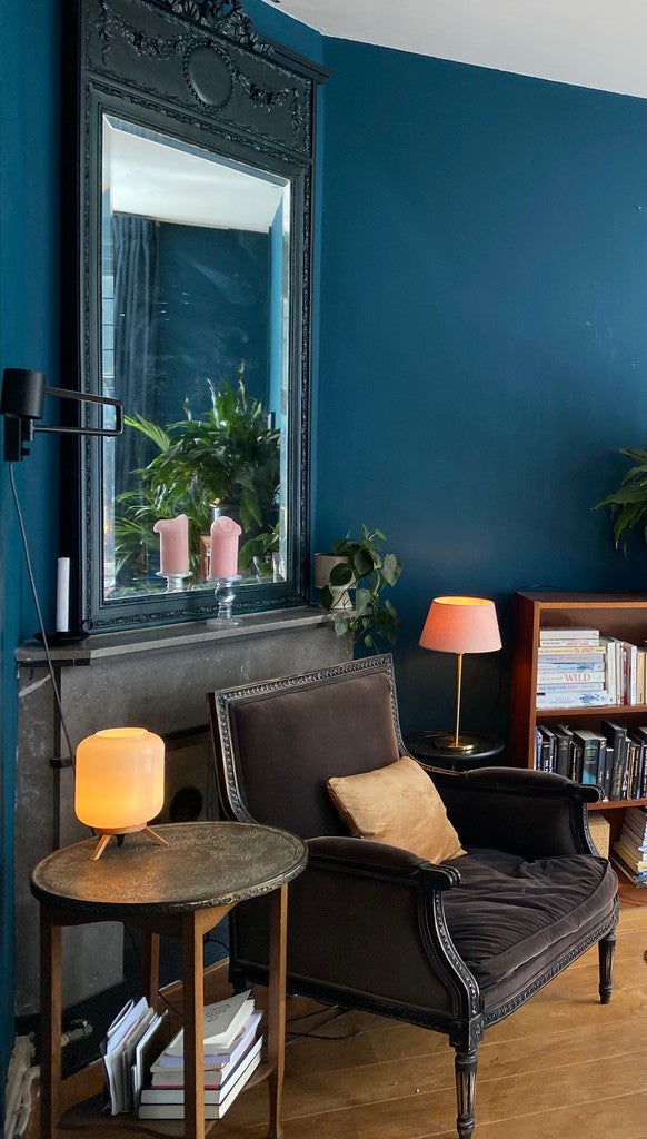 Living room with dark blue walls, a gray armchair, and decorative items.