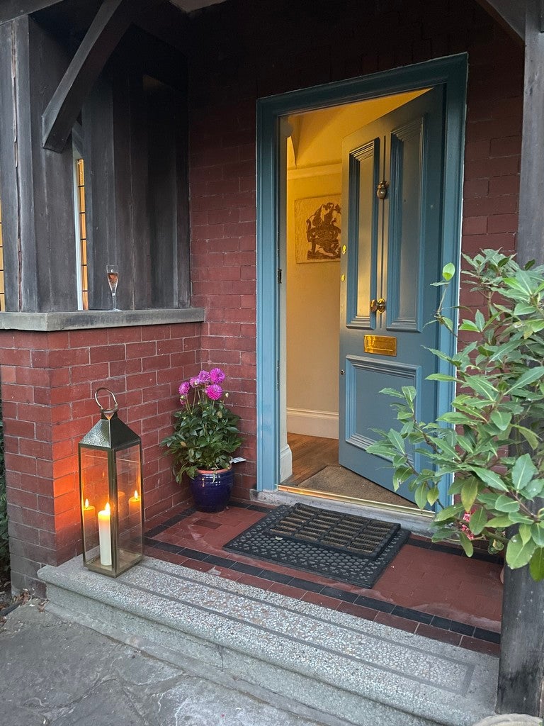 Front door of a house with a doormat, lantern, and flowers.