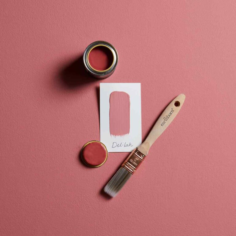 Red paint can, brush, and color swatch on a pink background