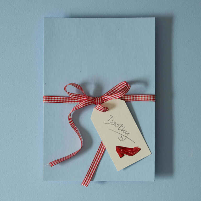 Blue card with a red gingham ribbon and tag on a light blue background