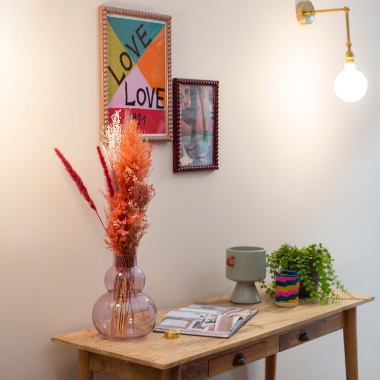 Small wooden table with decorative items against a wall with framed art